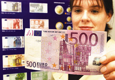 ¼ÚÃ¹¶r²¼¡B²{¶rAline Heurley from Flensburg checks a 500-Euro bank note in front of a poster showing the new Euro currency during a public presentation of the new Euro at the branch office of the German Federal Bank in Flensburg, northern Germany, on Saturday, Sept.1, 2001. The new currency will be introduced on Jan.1, 2002, in twelve European countries. EDS note: Bank note is perforated 'invalid' because of security reason during public presentation. (AP Photo/Heribert Proepper)