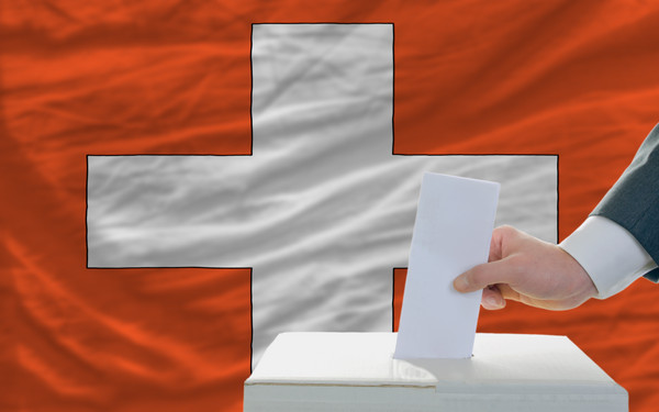 man voting on elections in swiss in front of flag